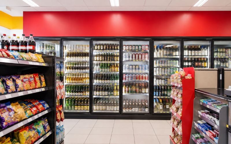 Refrigerated cooler stocked with beer, wine, and beverages inside a brightly lit Mexican convenience store
