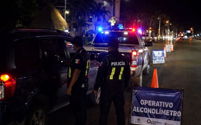 Mexican police officers conducting a DUI sobriety checkpoint on a road at night with flashing police vehicle lights