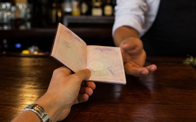 Tourist handing an open passport to a bartender at a bar in Mexico for age verification